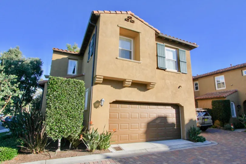 A perfectly trimmed rectangle hedge sits next to a garage at Allassio homes