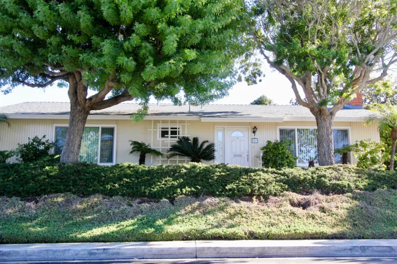 A small house in the Bay Cliff Village with two trees.