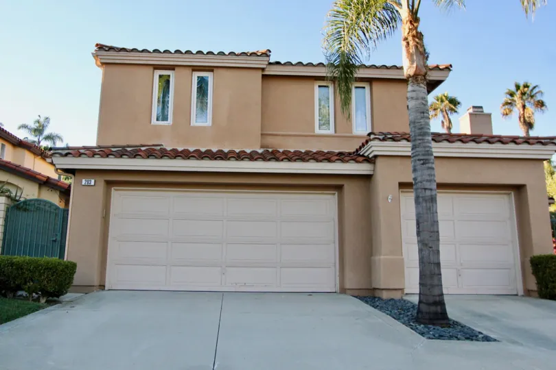 Front view of a large house with a palm tree at dusk