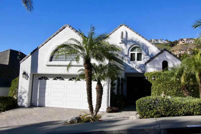 A bowed palm tree sits in a garden patch near a sidewalk in the Las Marias homes