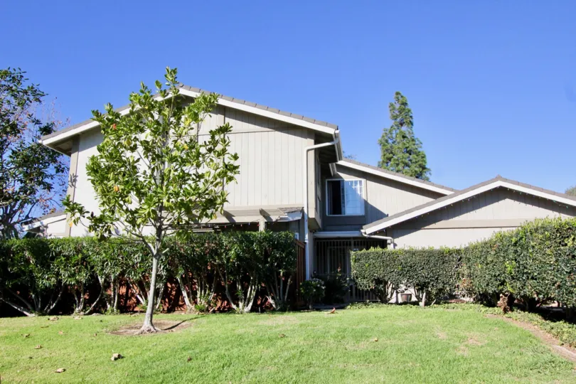 A beautiful house with a surround of trees and a garden at the front and a beautiful sculptery at the front.