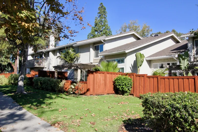 THE HOUSE IN THE MIRA COSTA VILLAS WITH THE LAWN, TREES, PLANTS, WOODEN DOOR, BANANA TREE