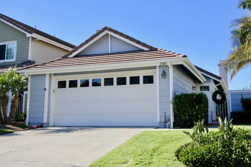 Bungalow style house with a double car attached garage and sizable front lawn with hedges