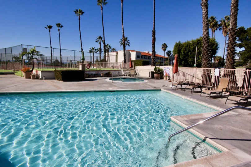 A big swimming pool with full of water and relaxing chairs around it in Ocean Fairways. q