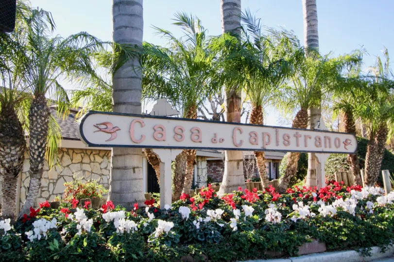 A signage perched against tall trees in the Casa De Capistrano community.