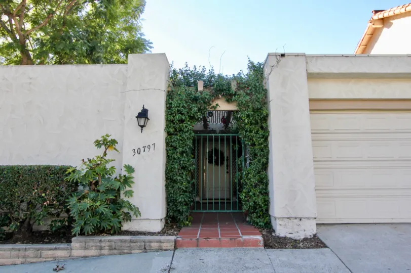 A green color gate with plants in the Casitas Capistrano.