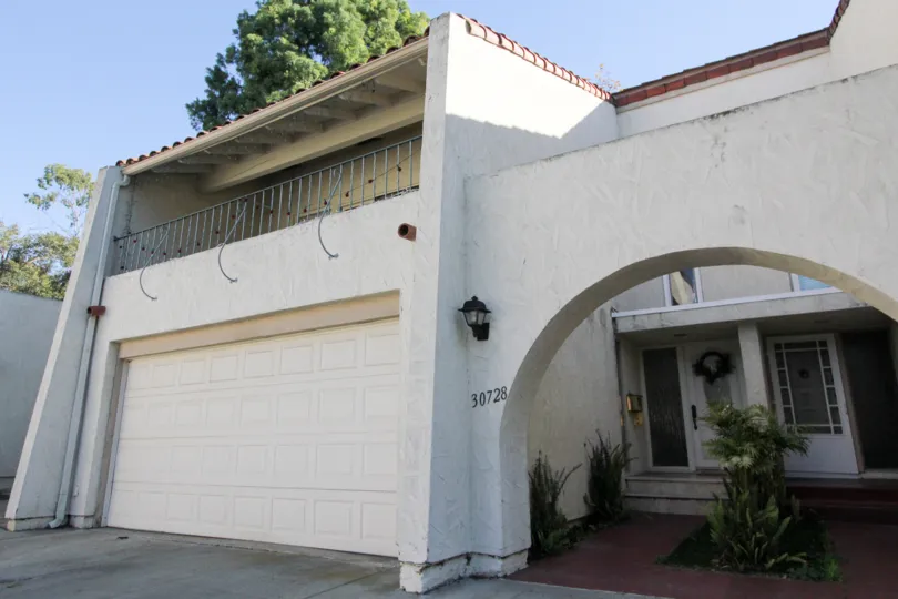Spanish style house with large garage and archway on a clear Southern California day.
