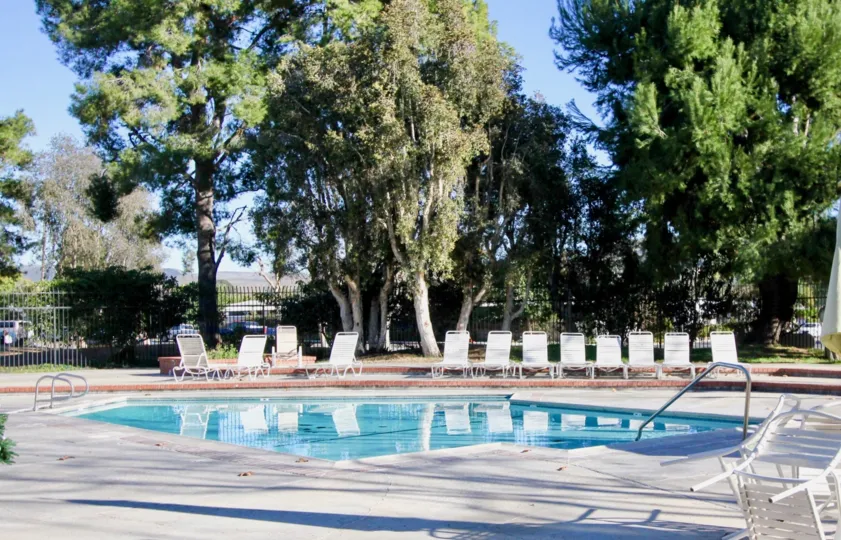 This image shows the beautiful swimming pool with the lot of trees, chairs looks beautiful view that is situated in the community of Casitas De Alipaz