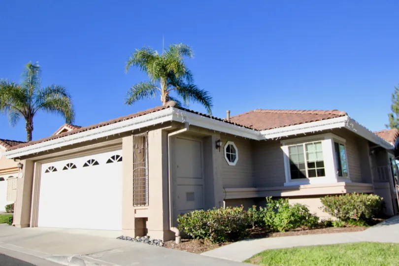 A sunny day by a Loma Vista house with palm trees behind it and bushes on one side