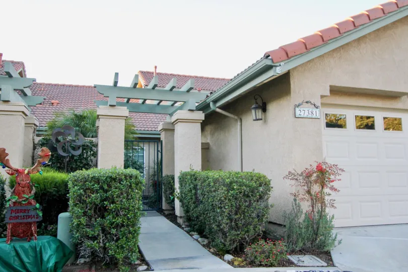 Front sidewalk between shrubs to a ceramic tile roof