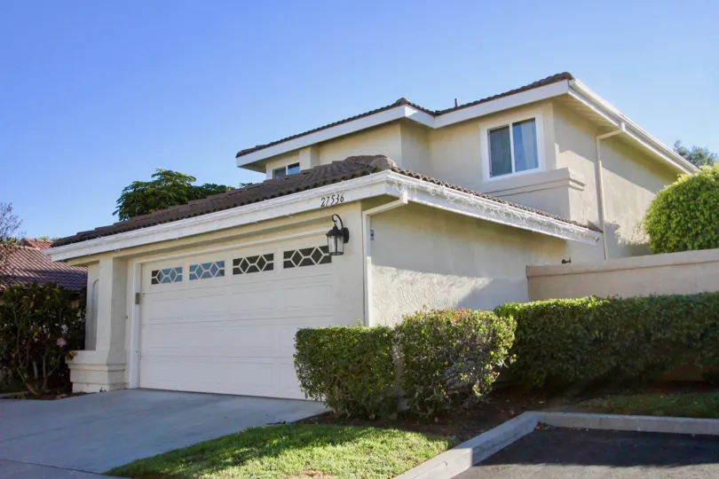 A sunny day at a house in Mesa Vista South with a driveway and bushes and grass surrounding the house