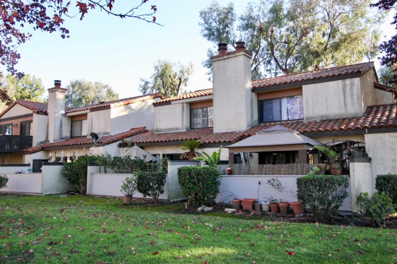 large connected backyard with shrubs and pottery at the rear of the home
