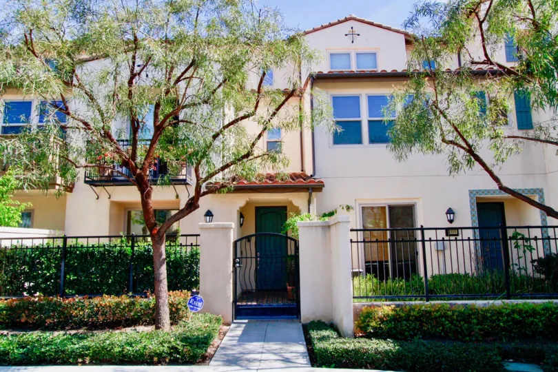 A white gated apartment building on a sunny day in Avenue E