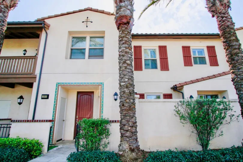 A bright day in the Avenue E with some palm trees and entrance door.