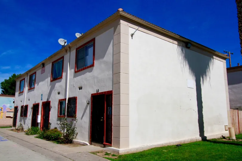 A white building of Bishop Manor with red doors and windows on a sunny day