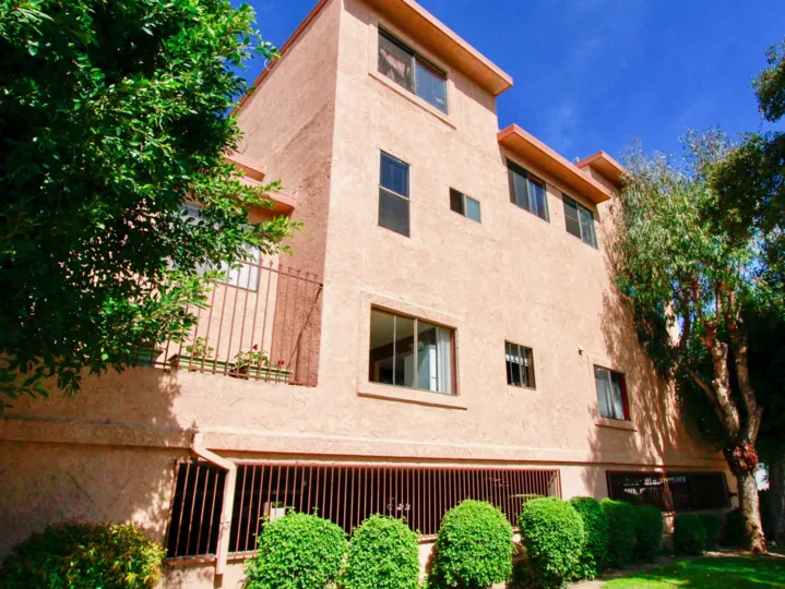 A pink color bunglow with three floors and a large garden surrounding it inside chestnut Manor community