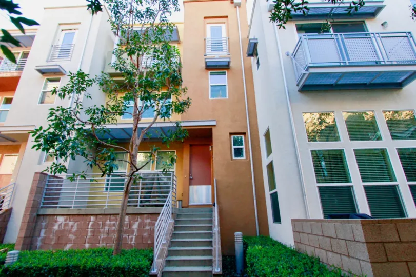 A multi storyed house with steps leading to a narrow front door in the city place community