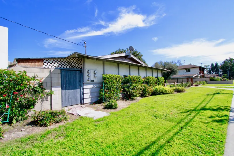 A small house with a big wooden gate alonga lawn in the Garden Villas community