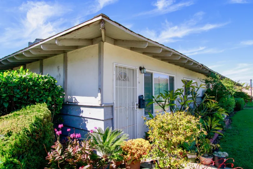 A white house with several plants around the house in garden villas community in santa ana, california.