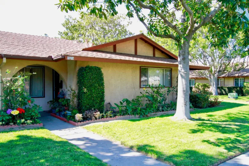 Near the entrance of house has full of flower pots and flowers with lawn and trees in La Linda Villas