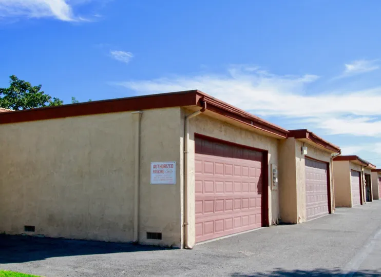 Garages with red doors in the La Linda Villas community on a sunny day.