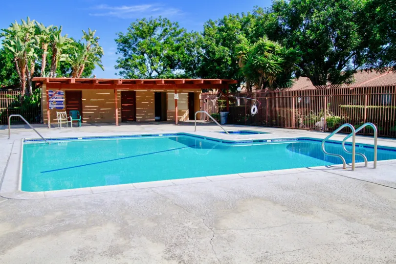 A pool in La Linda Villas enclosed by a wooden fence on a sunny day.