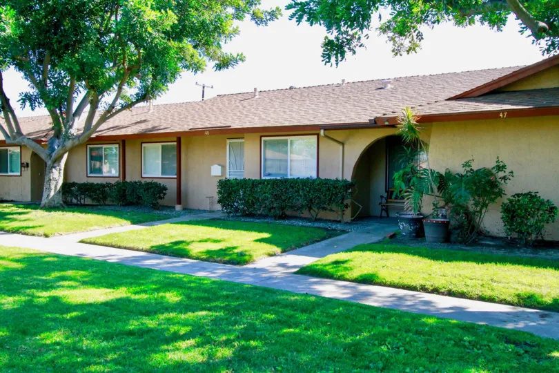 A beautiful day in the La Linda Villas with a lawn in front of a building.