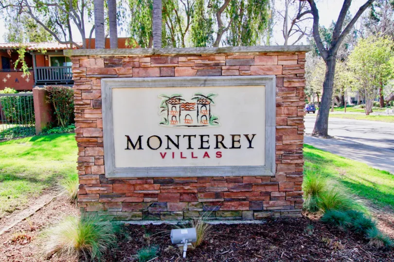 The brick sign of the Monterey Villas community on a sunny day.