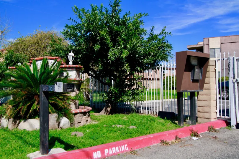 Near the entrance gate of Newhope Garden, marked as No parking at the side with lawn and trees