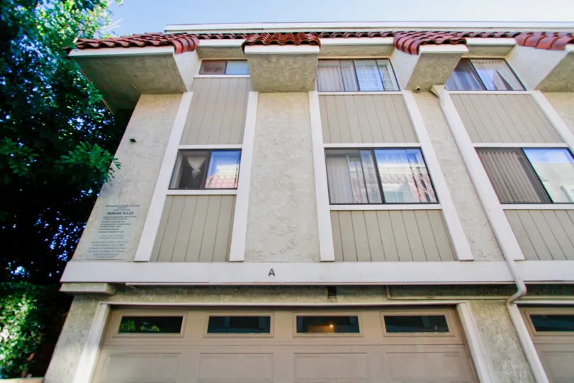 A big beautiful white and grey color apartment in the North Broadway Townhomes with glass windows and big trees.