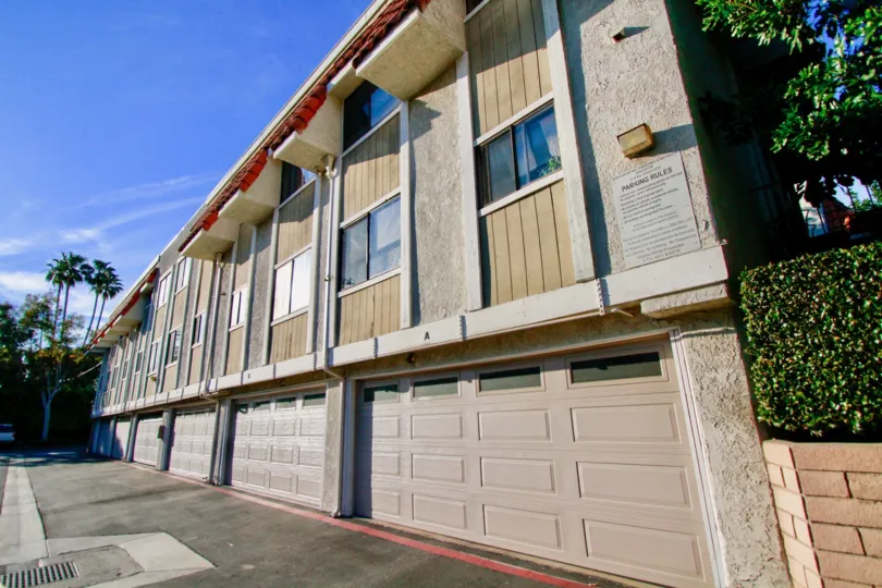Side view of a large building with multiple garage doors along a pathway in the North Broadway community