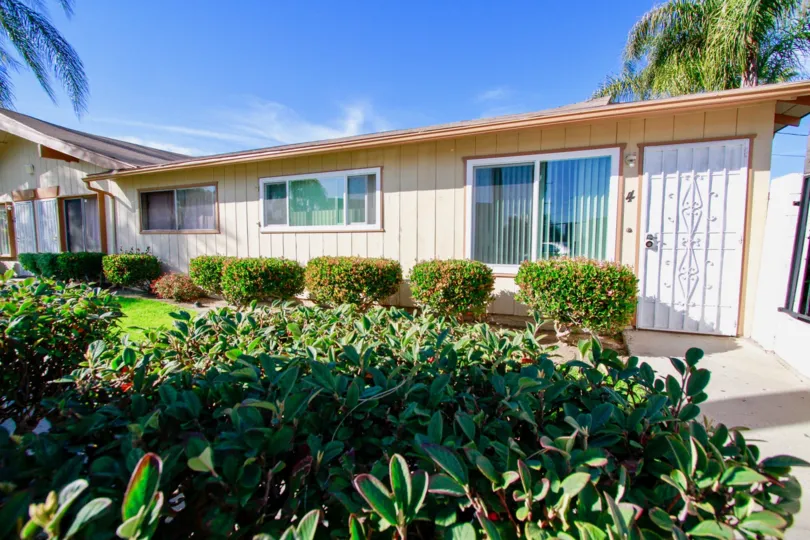 a tan house with bushes along the front at regency villas community in santa ana, california.
