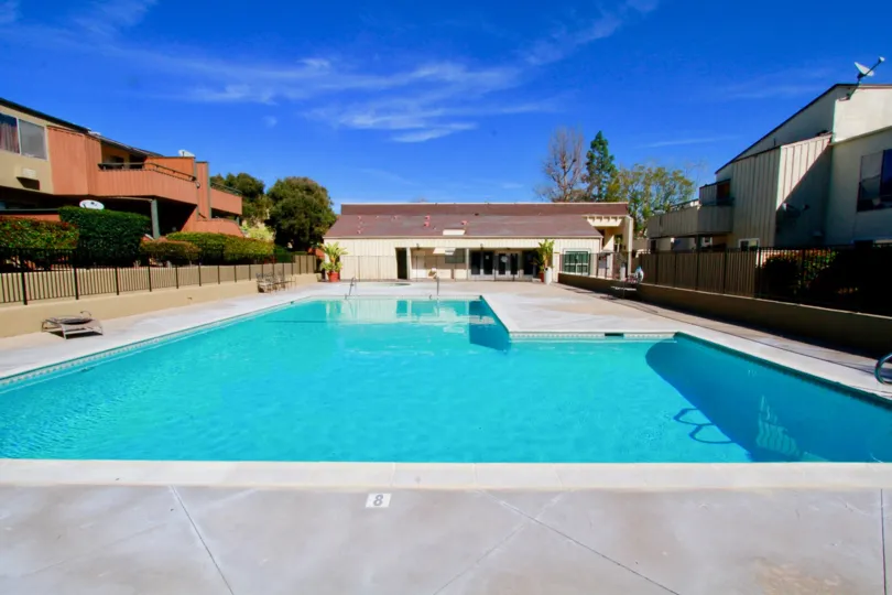 A gated pool in the South Coast Terrace community with benches on a sunny day.