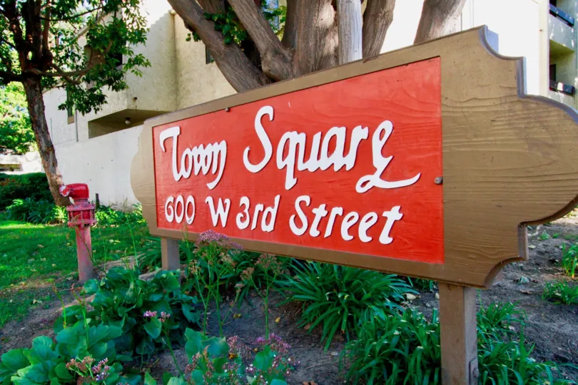 the board at the entrance indicates the Town Square address placed between the plants and bushes