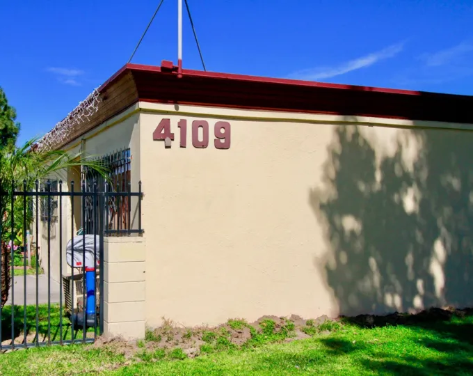 The street address of Village Gardens with a gate on a sunny day.