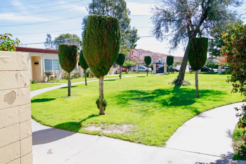 Front to villa in Village Gardens has a place with Lawn, trees with plants