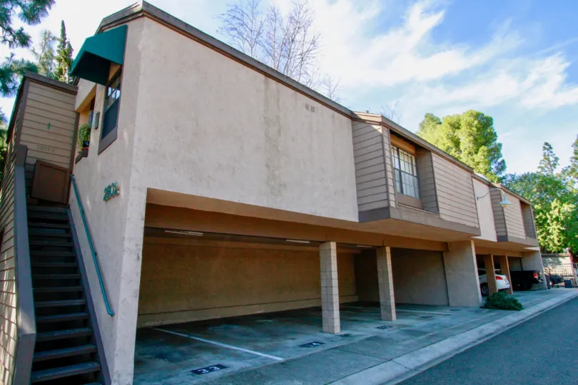 A apartment building in Woodlake with a garage and a staircase on a sunny day.