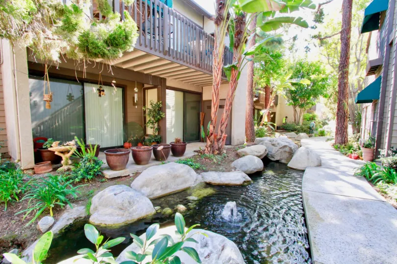 A stream in the Woodlake community with a fountain and rocks.