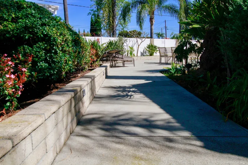 Seating chairs and dinning tables is present at the pathway with bushes and trees in Woodlyn North