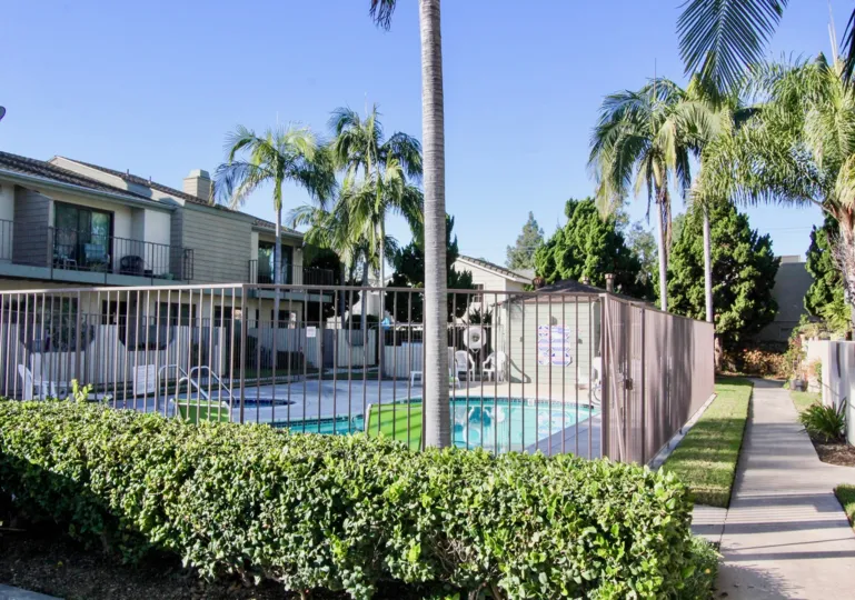 THE BUILDING IN THE CERRITOS GARDENS WITH THE SWIMMING POOL, CHAIRS, TREES