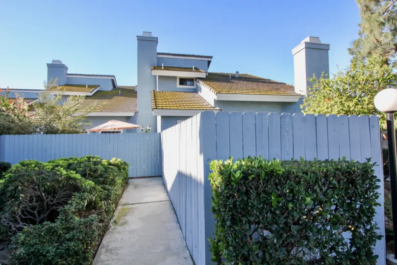 A large bunglow with white wooden fencing surrounded by plants