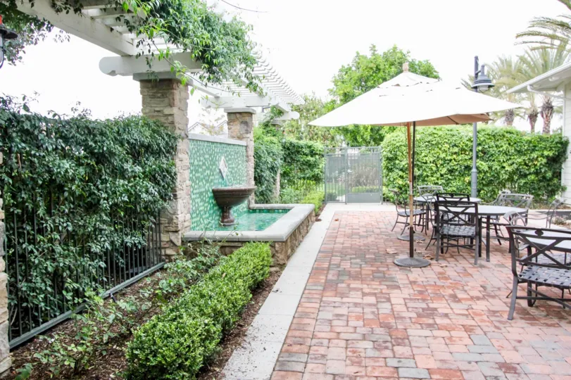 An overcast day in a patio in the Ainsley Park area with tables, umbrellas, and greenery surrounding the area