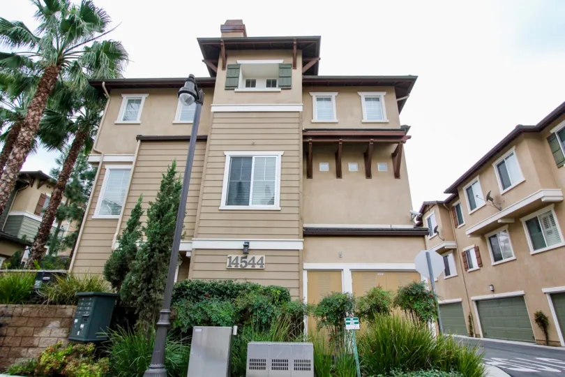 A sunny day at the three story Arbor Walk community with private ground level garage parking, new windows and palm trees