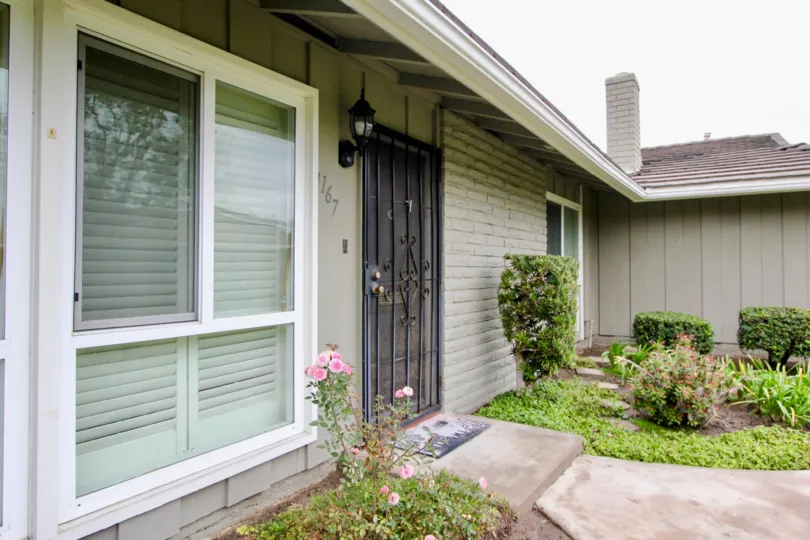 Bungalow style house with ample front yard and decorative exterior brick wall with wrought iron security door at Broadmoor Park