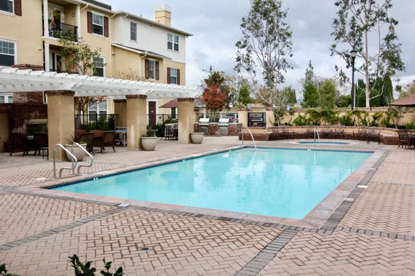 A pool beside a porch of a three storied housing complex