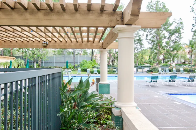 The swimming pool area, complete with chairs and a lovely pergola in the community of Corte Villa in Tustin, California