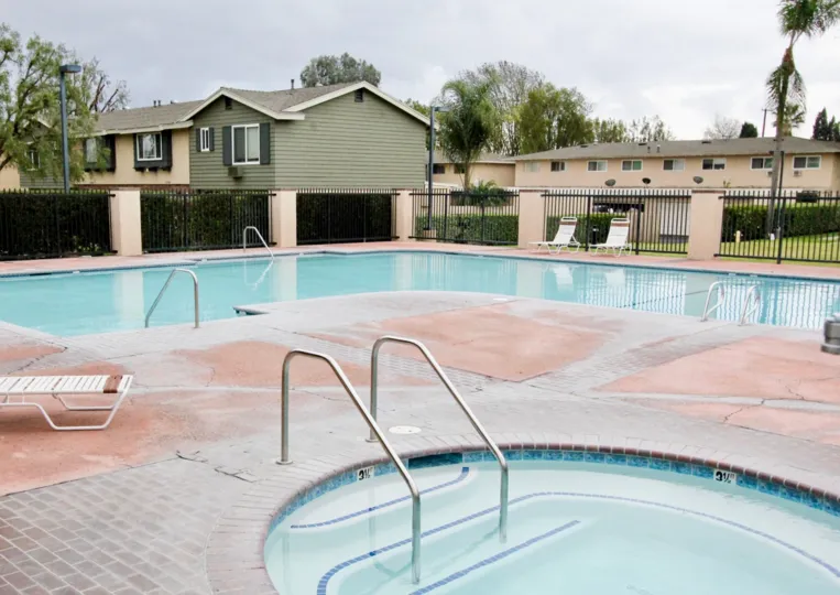 Resident's pool and hot tub in Influential Square in Tustin, California. Fenced pool area and lounge chairs around pool.