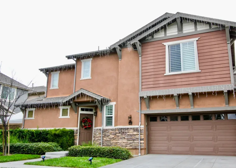 An overcast day by a Lindy Crossing house painted brown with a Christmas wreath on the front door
