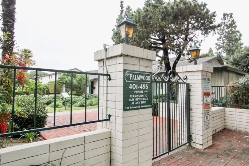 Gated security entrance with decorative lights and wrought iron fencing and brick pathway at Palmwood Gardens