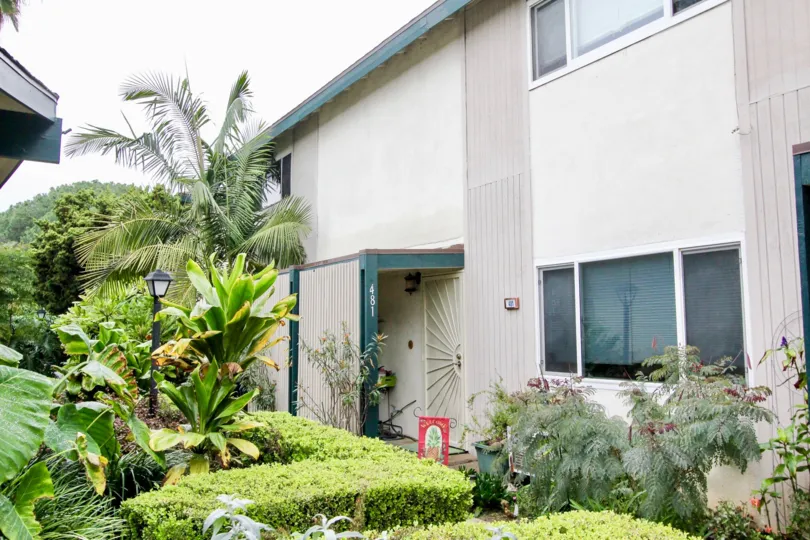 A simple two-storey residence with white and blue paint in the Palmwood Gardens community.